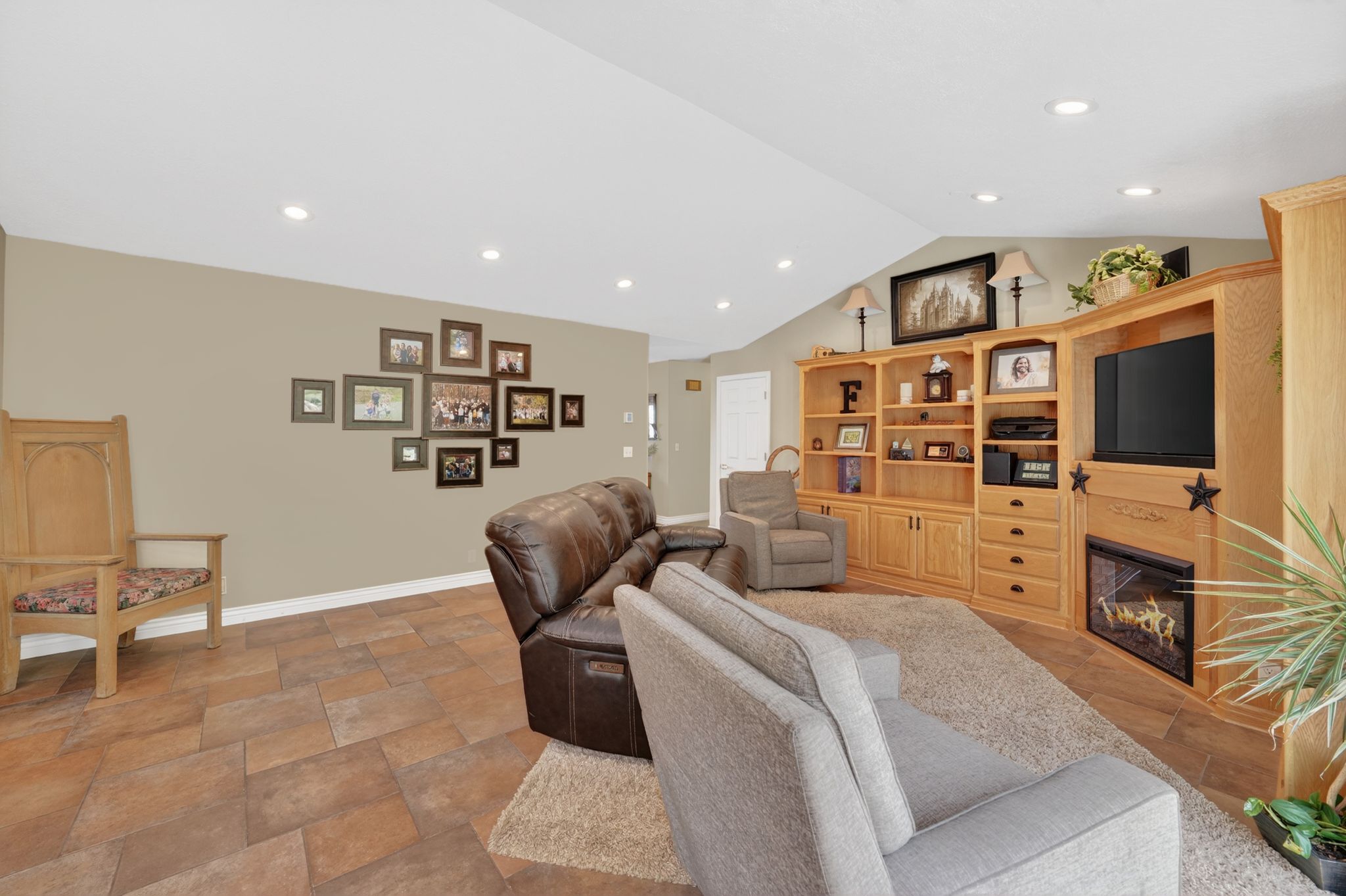 Living room with a glass covered fireplace, stone finish floors, and recessed lighting