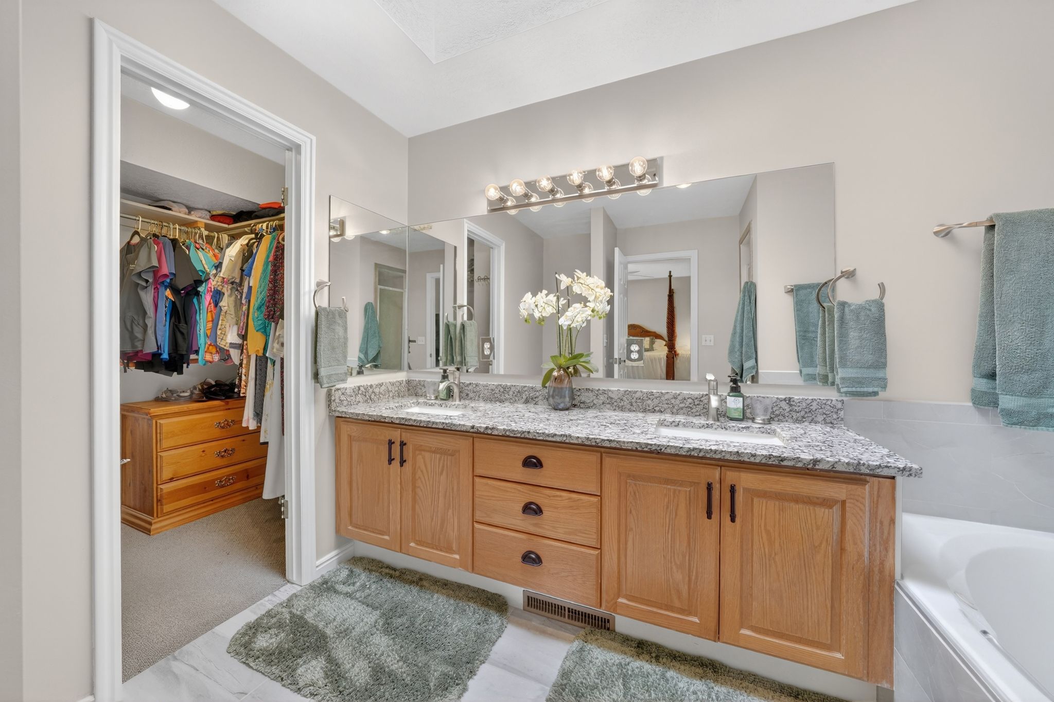 Full bath featuring double vanity, a walk in closet, and a bath
