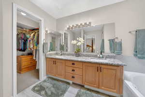 Full bath featuring double vanity, a walk in closet, and a bath