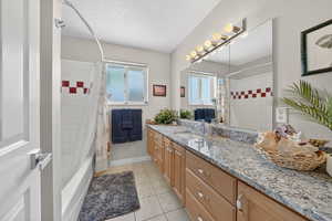 Full bathroom featuring vanity, shower / bathtub combination with curtain, light tile patterned flooring, plenty of natural light, and a textured ceiling