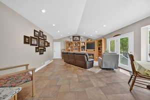 Living room with stone finish floors, recessed lighting, and a warm lit fireplace