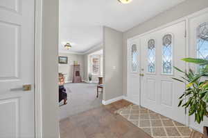 Foyer entrance featuring carpet flooring, ornamental molding, stone finish flooring, and a textured ceiling