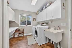 Laundry area with light wood-type flooring, washer and clothes dryer, cabinet space, and an office area