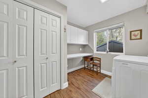 Laundry room featuring cabinet space, light wood-style floors, an office area, and washing machine and clothes dryer