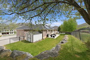 Back of house featuring a shed, solar panels, brick siding, a fenced backyard, and a patio