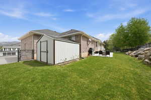 View of home's exterior with a fenced backyard, a gate, a storage shed, and brick siding
