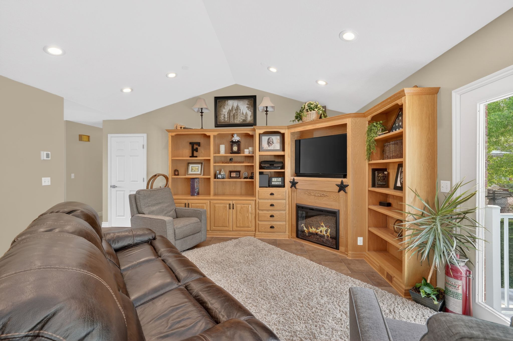 Living area with a glass covered fireplace, recessed lighting, and light tile patterned floors