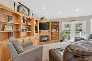 Living area featuring vaulted ceiling, recessed lighting, and a glass covered fireplace