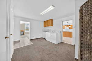 Laundry area featuring light colored carpet, light tile patterned flooring, cabinet space, a glass covered fireplace, and a heating unit