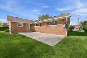 Rear view of property with a patio, a yard, brick siding, and a chimney