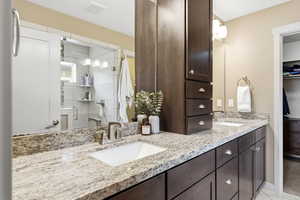 Primary bathroom with double vanity, and upgraded cabinetry with a spacious closet