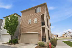 View of front of home with a garage, driveway, and a balcony