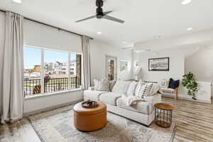 Living room with light wood-type flooring, a ceiling fan, and recessed lighting
