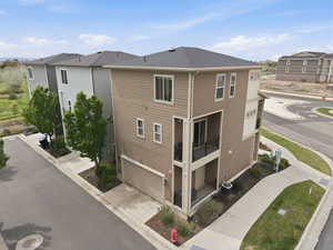 View of side of home with a garage, driveway, roof with shingles, and a residential view