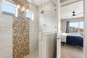 Ensuite bathroom with plenty of natural light, a stall shower, light colored carpet, and ceiling fan