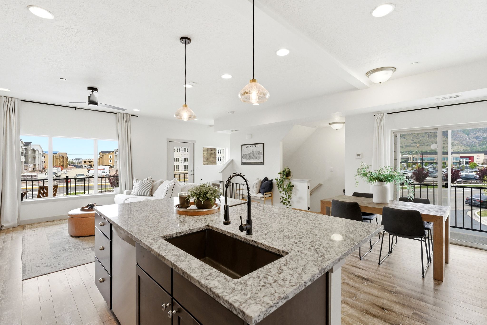 Kitchen featuring light wood-type flooring, an island with sink, open floor plan, and light stone counters