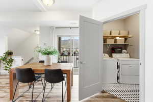 Laundry area featuring independent washer and dryer, light wood-type flooring, and vaulted ceiling
