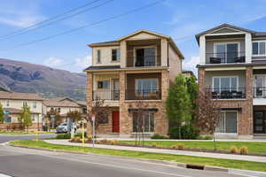 View of front of home with a balcony, a mountain view, brick siding, and a residential view