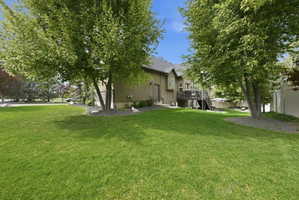 View of property exterior with a wooden deck, stucco siding, and a lawn