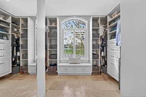 Walk in closet featuring light stone finish floors