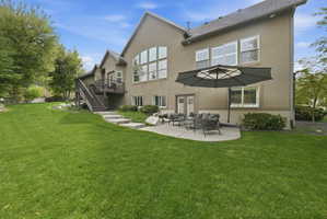 Rear view of property with a patio area, stucco siding, a lawn, and a wooden deck