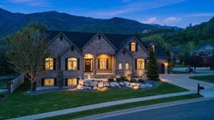 French country style house with stone siding, a yard, a mountain view, and concrete driveway