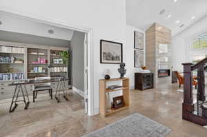 Office space with a tile fireplace and a high ceiling