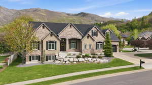 French country inspired facade with stone siding, a mountain view, stucco siding, and driveway