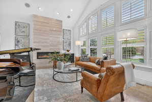 Living room with vaulted ceiling, a tile fireplace, and recessed lighting