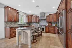 Kitchen featuring a kitchen breakfast bar, premium appliances, a kitchen island, wood finish cabinetry, and recessed lighting