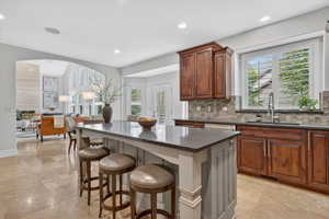 Kitchen featuring a kitchen breakfast bar, open floor plan, backsplash, arched walkways, and a kitchen island