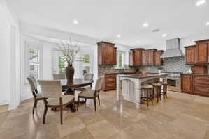 Kitchen featuring a kitchen breakfast bar, stainless steel stove, a kitchen island, dark stone counters, and recessed lighting