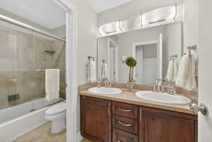 Full bath with double vanity and combined bath / shower with glass door