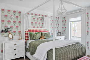 Bedroom featuring crown molding, wallpapered walls, and hanging lights