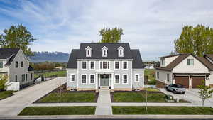 View of front of home with roof with shingles, a mountain view, and driveway