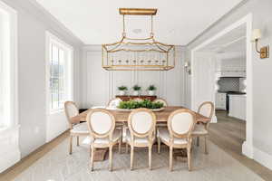 Dining area with light wood-type flooring, ornamental molding, and a decorative wall
