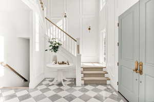 Staircase with a decorative wall, a high ceiling, and tile patterned floors