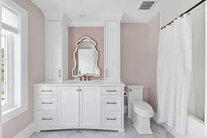 On-suite full bath featuring vanity, plenty of natural light, shower / tub combo, and light marble finish floors
