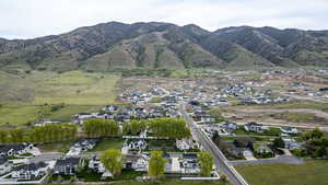 Aerial view of property and surrounding area featuring nearby suburban area and a mountain backdrop