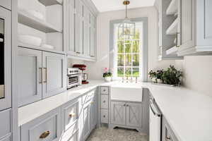 Dual tone kitchen featuring open shelves, light stone counters, hanging light fixtures, dishwasher, and two tone cabinetry