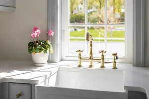 Kitchen view of a sink and light stone counters