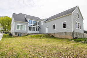 Rear view of house featuring a yard and roof with shingles