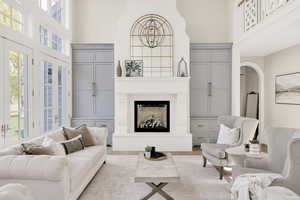Living area with a fireplace with raised hearth, arched walkways, a high ceiling, and wood finished floors