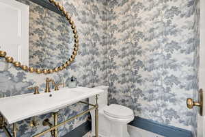 Half bathroom with a sink and wallpapered walls