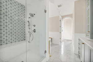 Full bath with a wainscoted wall, a shower stall, vanity, and a decorative wall