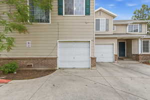 View of front facade featuring a garage, brick siding, and driveway