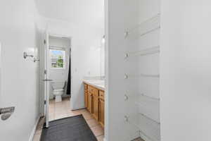 Bathroom with vanity, light tile patterned floors, and a closet