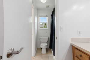 Full bath featuring vanity, light tile patterned floors, and curtained shower