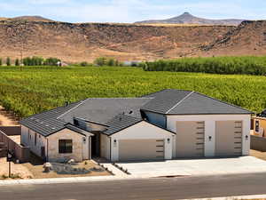 View of front of house with agricultural area, stone siding, a view of rural / pastoral area, and a mountain view