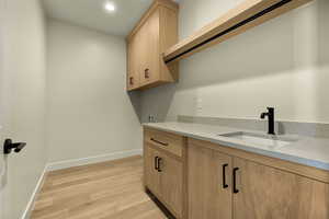 Laundry area with light wood-type flooring, cabinet space, washer hookup, and recessed lighting